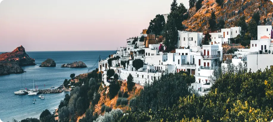Buildings on the hill near the ocean with boats docked